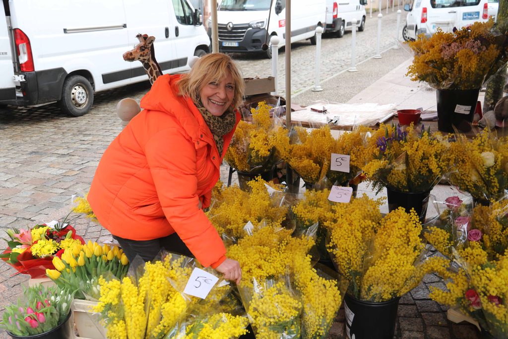 Foire Grasse 2025. Une vendeuse tout sourire avec ses bouquets de mimosas.